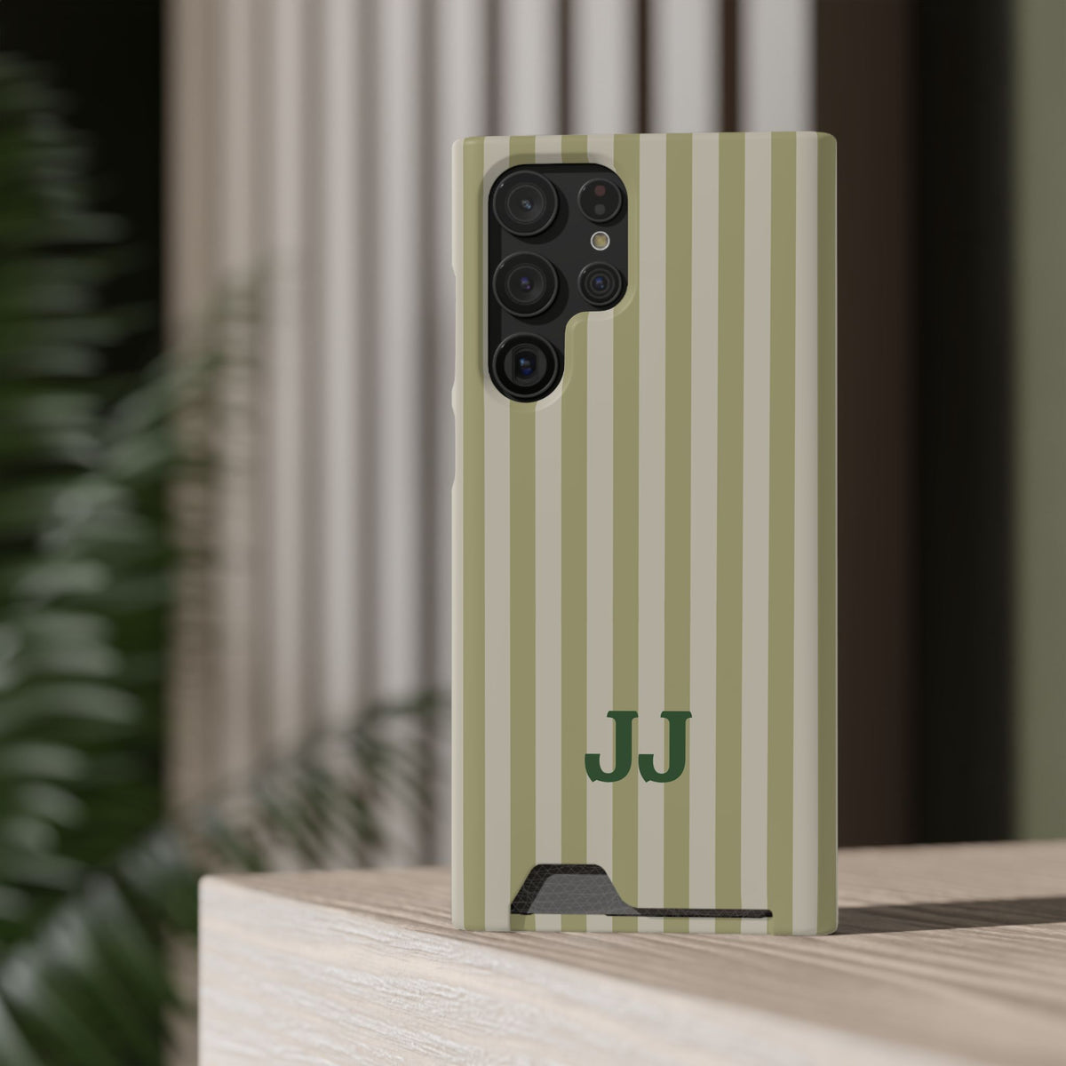 Sage Cabana Stripe card holder phone case on a ledge