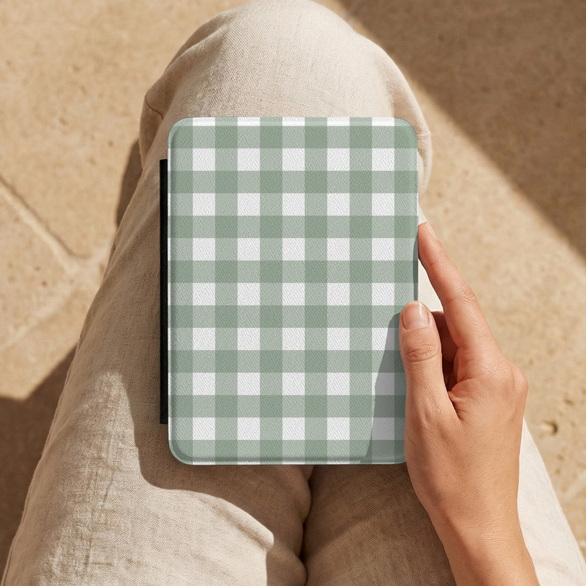 Sage Gingham Kindle case held on the lap while reading