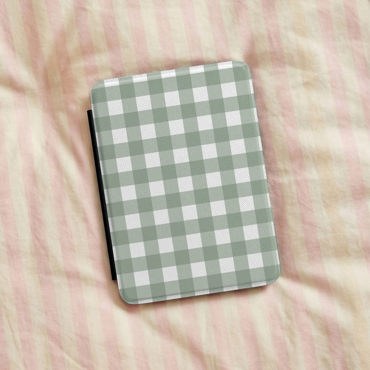 Sage Gingham Kindle case lying on pink striped bedding