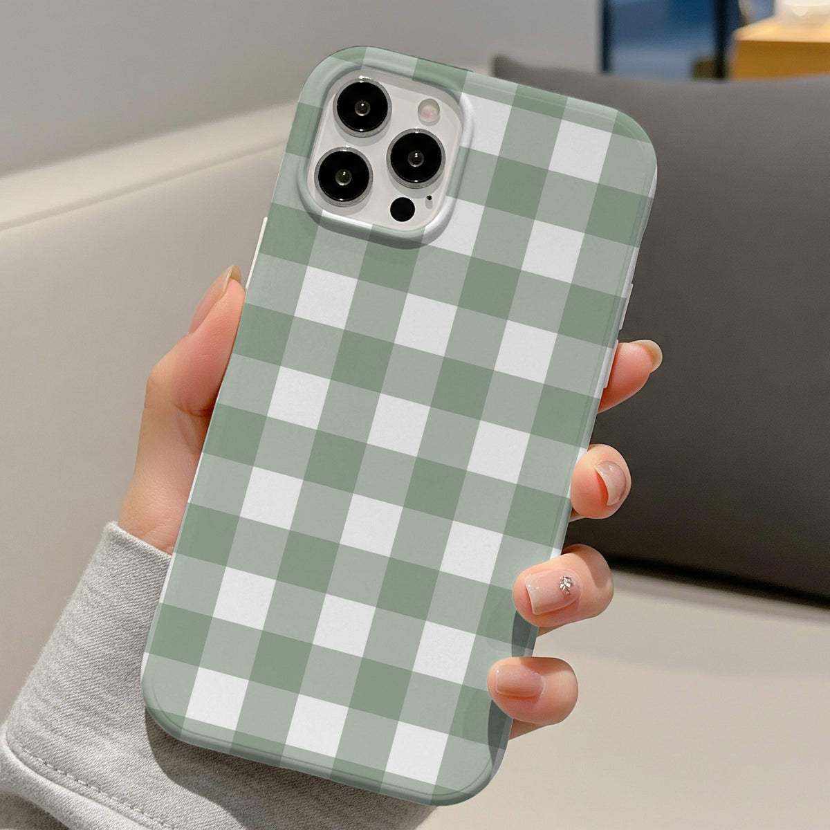 Sage Gingham tough phone case held in hand on a sofa