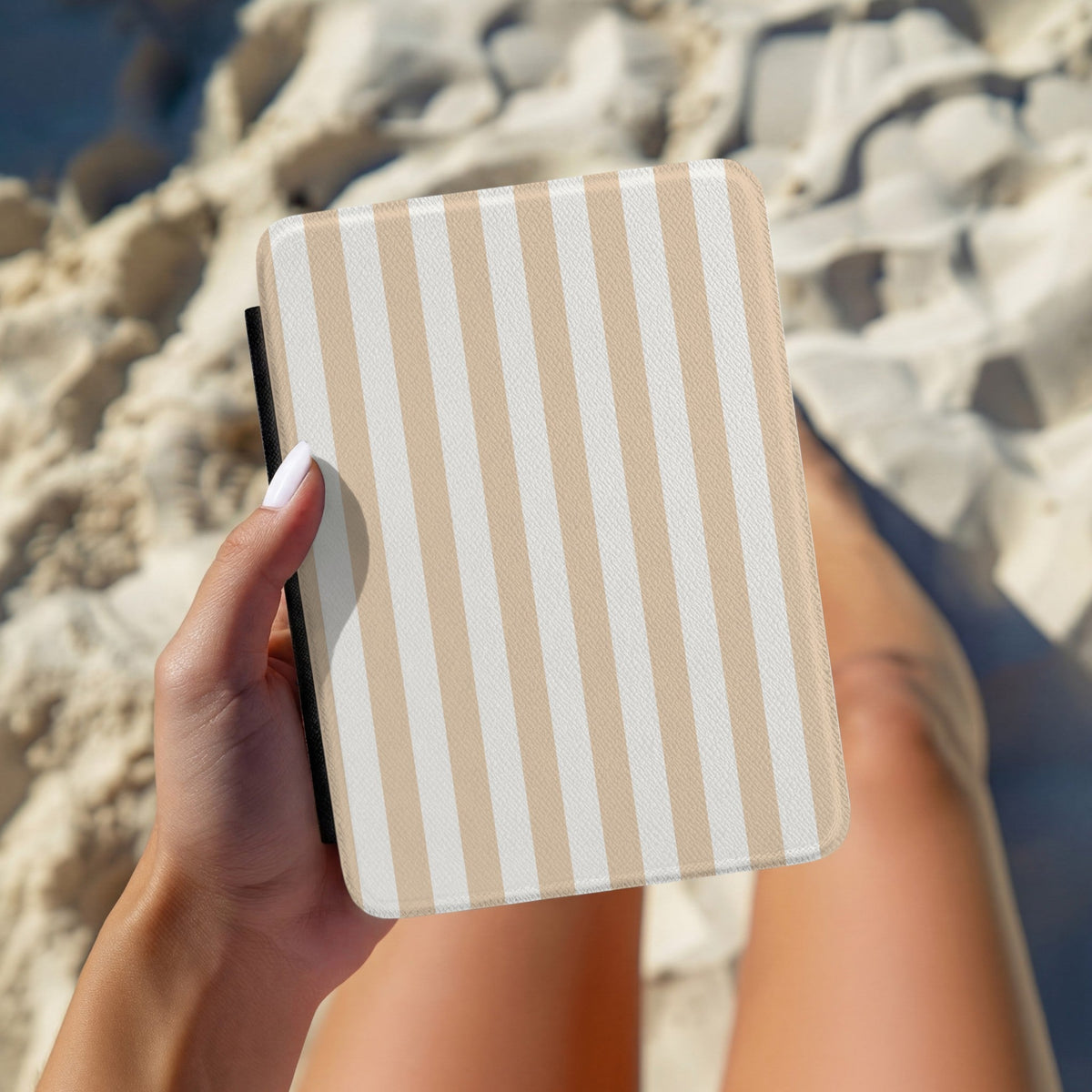 Hand holding a personalised sand cabana stripe Kindle case outdoors