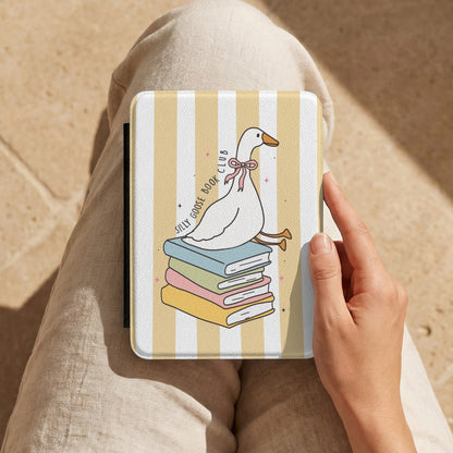 Hand holding the Silly Goose Book Club Kindle case on a lap