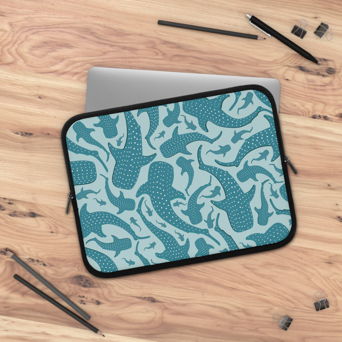 Teal Whale Shark laptop sleeve on a wooden desk with a laptop sliding in