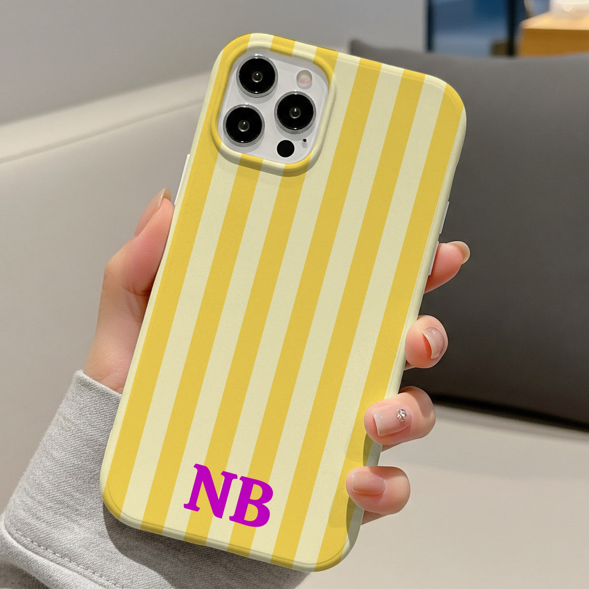 Yellow cabana stripe phone case with initials, held in one hand at a desk