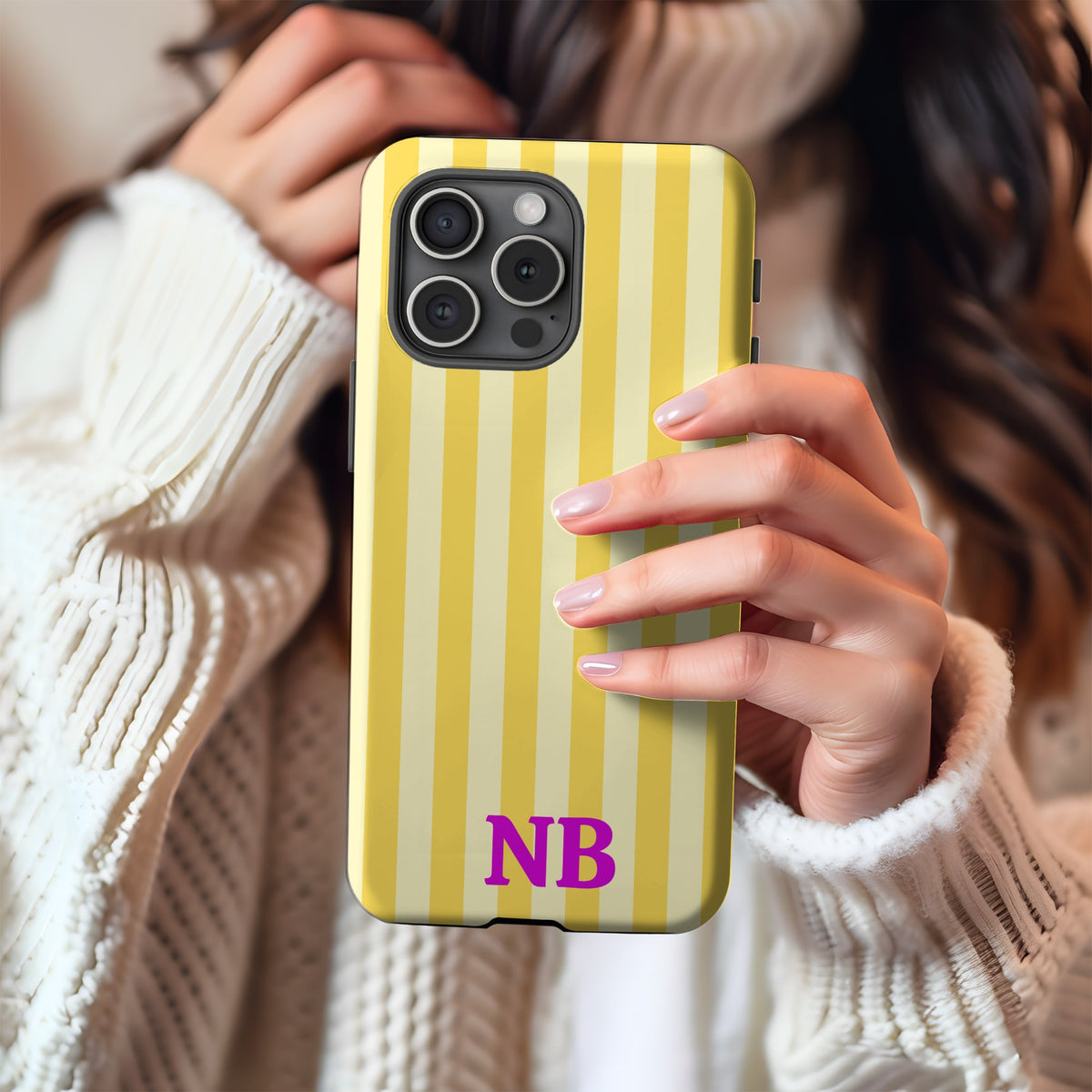 Yellow cabana stripe phone case held in hand against a cream knit sweater